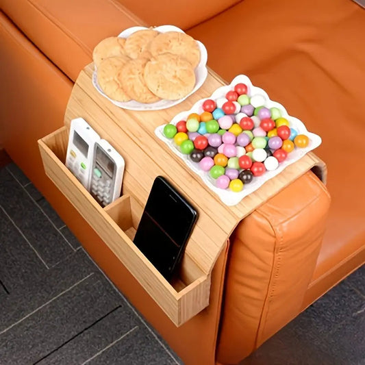 Wooden tray attached to an orange couch with snacks and a phone on it.