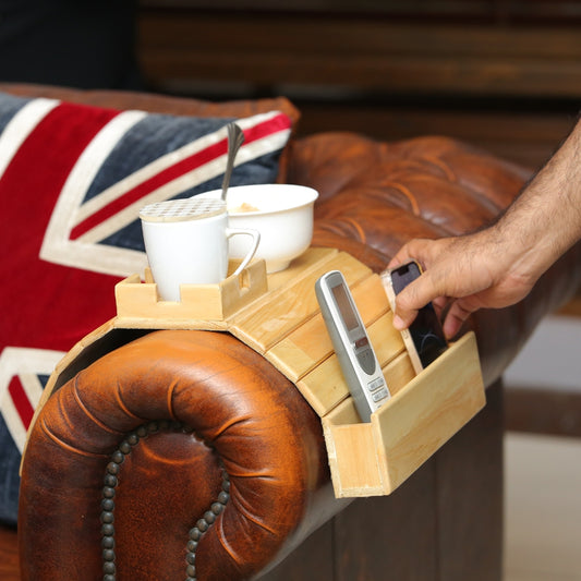 Wooden tray with cups and phone on a brown leather armchair with a Union Jack flag in the background.