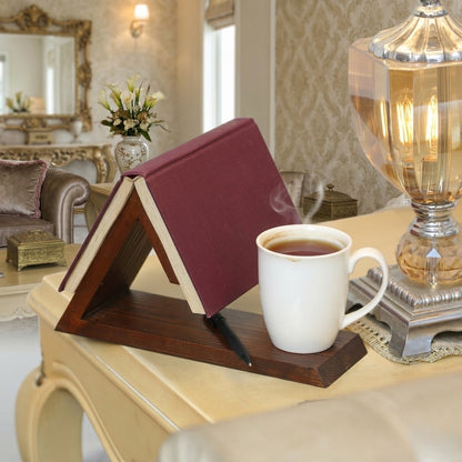 Book stand holding a book next to a cup of tea on a table in a cozy room.