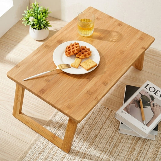 Wooden table with a plate of waffles, a glass of juice, a fork, and books on a carpeted floor.